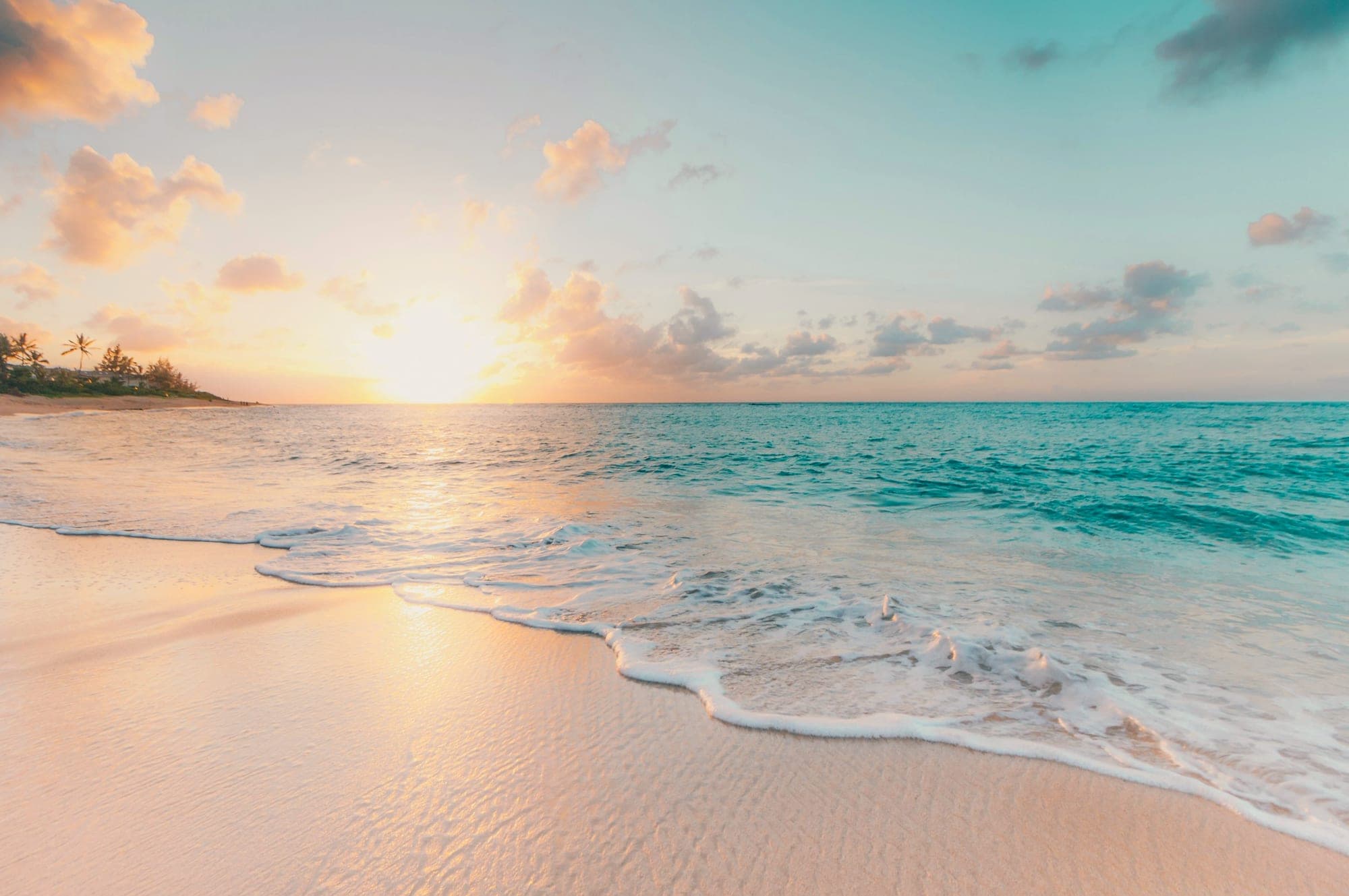 Turquoise sea meeting soft white sand under a clear sky